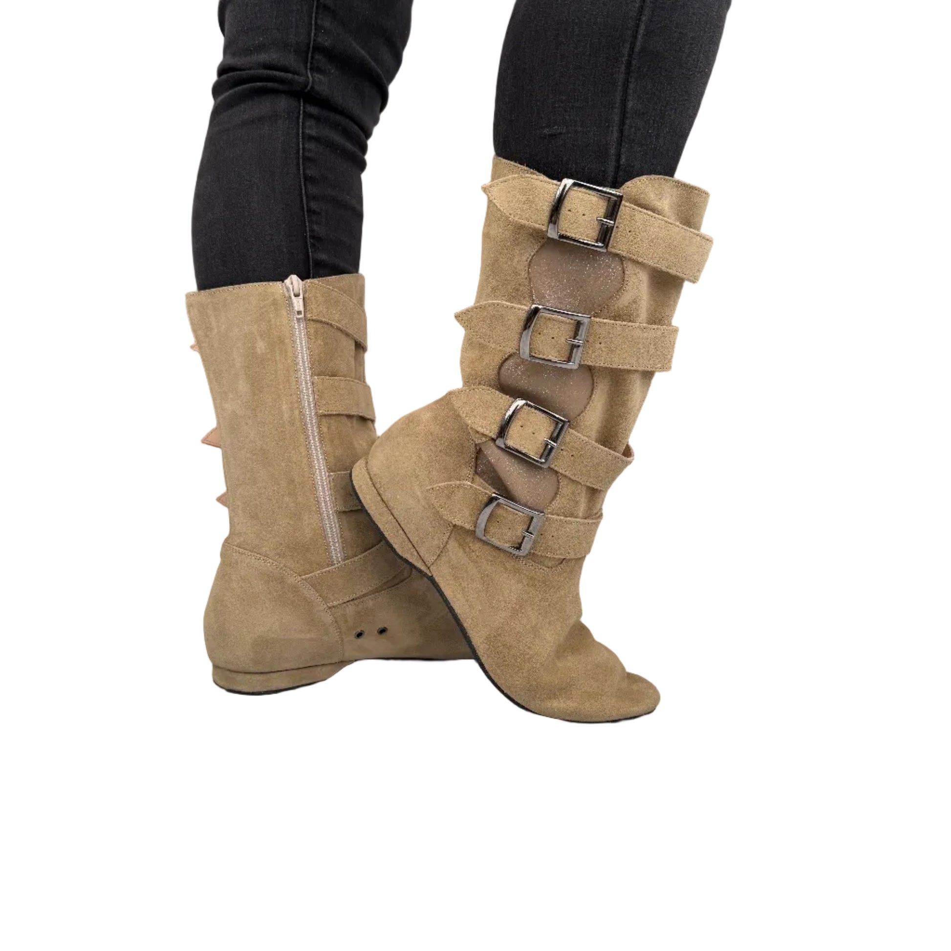 Tan suede boots with buckles worn by a person on a neutral background