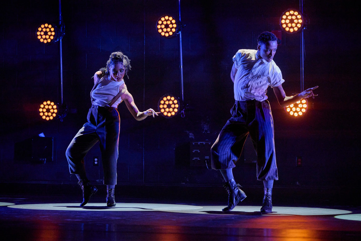 Two dancers performing on stage with dramatic lighting